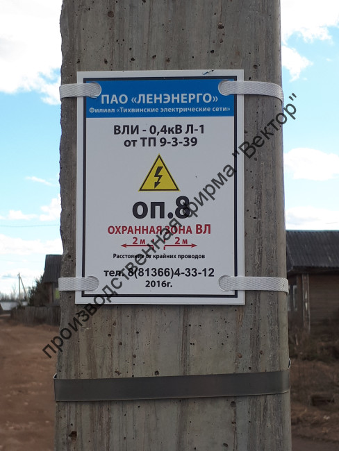Табличка «Охранная зона» на опору ЛЭП. Крепление к столбу на бандажную ленту, пропущенную через крепёжные отверстия.